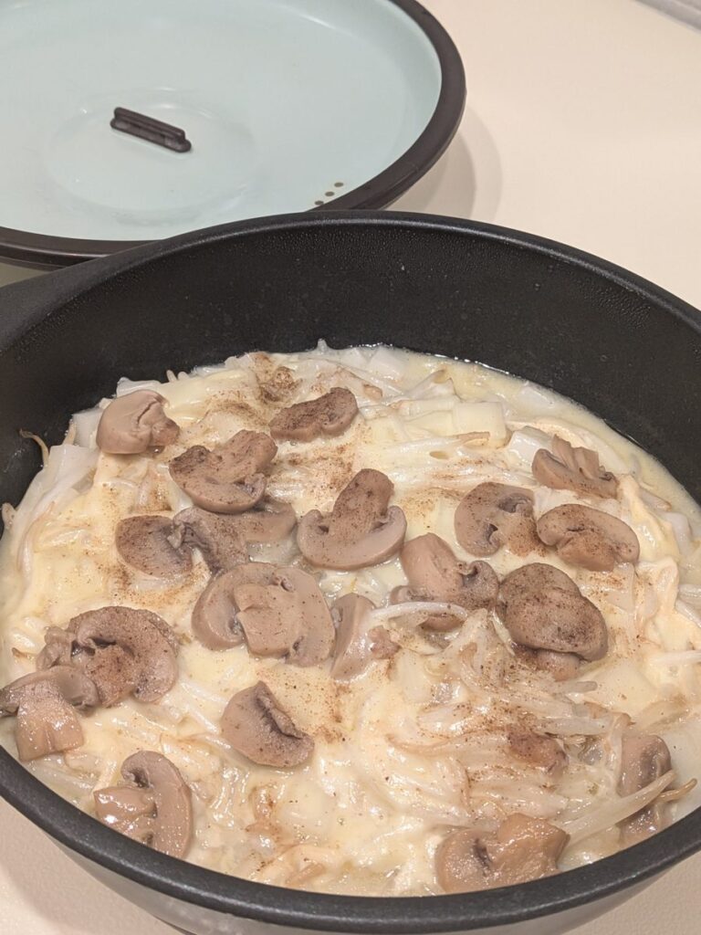 溶けたラクレットチーズにスライスマッシュルームをのせた、もやしとモチの焼き